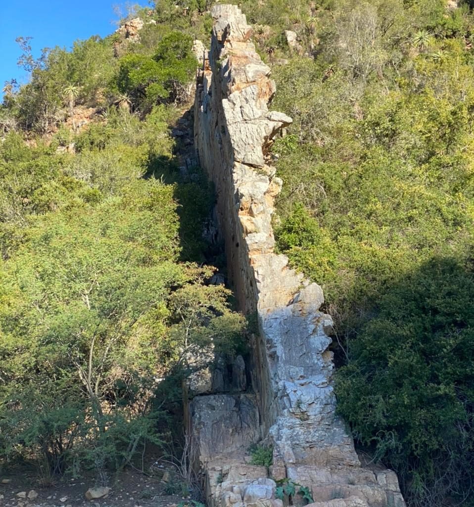 ‘n Vreemde rotsformasie wat soos ‘n muur lyk, net anderkant die begraafplaas, wat nou netjies is, baie naby aan die draad…